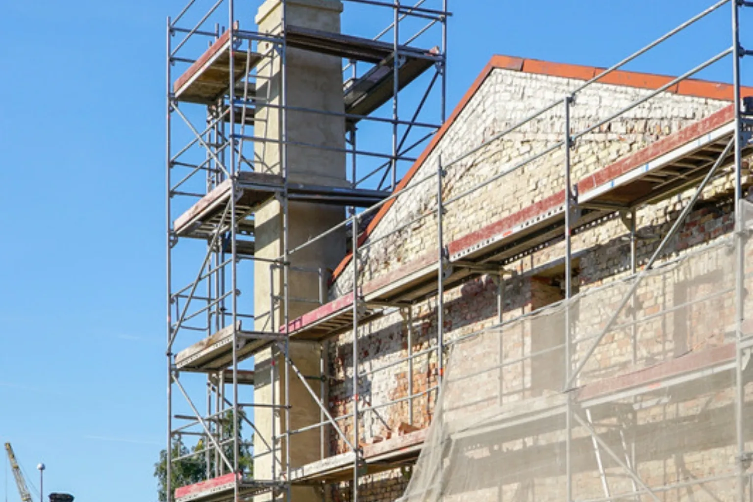 Stillads rejst op langs en hustavl og en skorsten under renovering